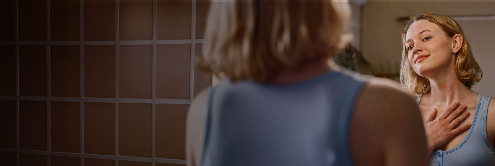 Woman looking in bathroom mirror