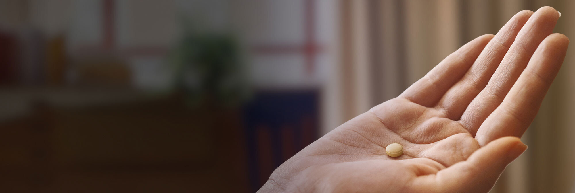 Pill in hand hero image. Patient portrayal, pill not actual size.