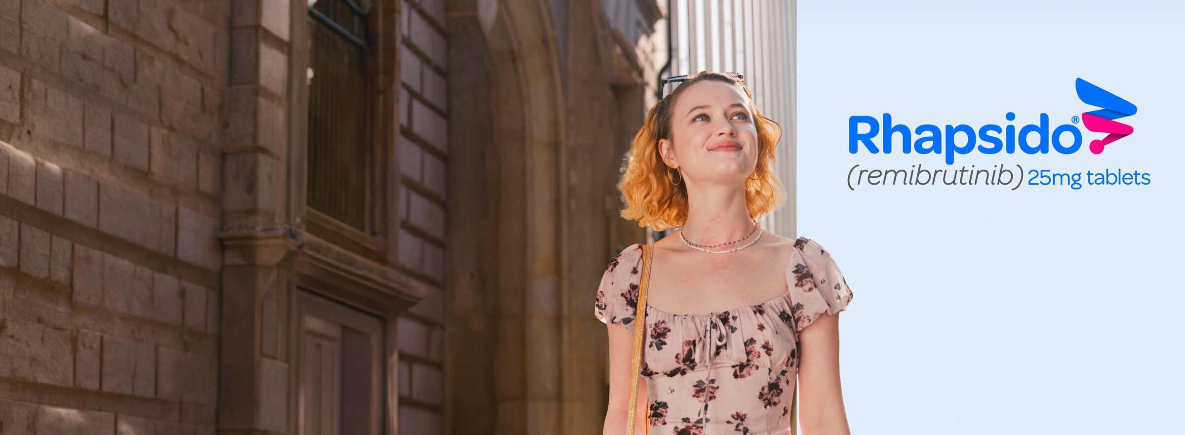 Woman walking down a city street in the sun.