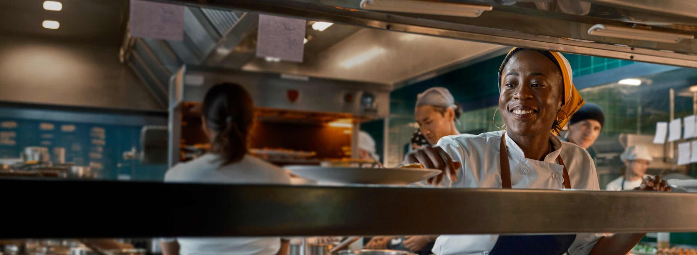 Woman at work in a restaurant kitchen smiling.